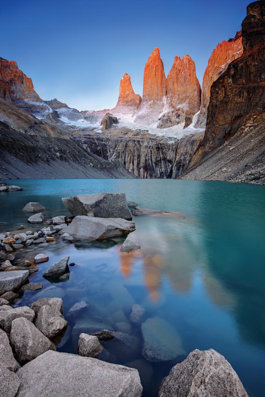 Las Torres del Paine iluminadas junto a un lago de agua turquesa